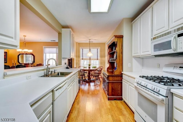 kitchen with decorative light fixtures, sink, white appliances, and white cabinetry