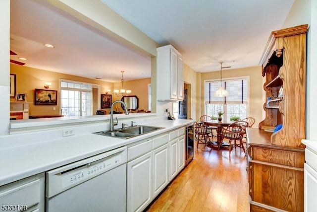 kitchen with decorative light fixtures, white cabinets, sink, and white dishwasher