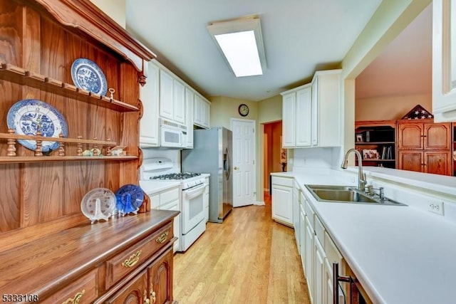 kitchen with light wood-type flooring, sink, white cabinets, and white appliances