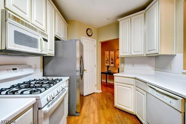 kitchen with white cabinetry, light hardwood / wood-style flooring, and white appliances