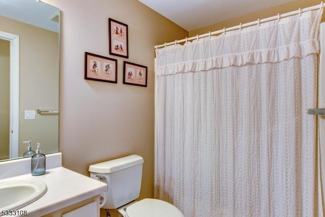 bathroom with toilet, vanity, and a shower with shower curtain