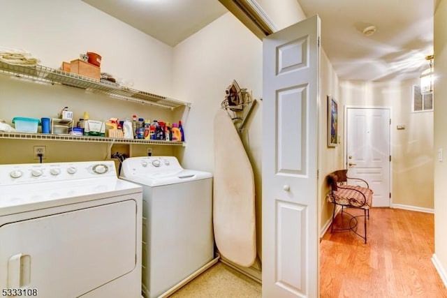 clothes washing area with separate washer and dryer and light hardwood / wood-style floors