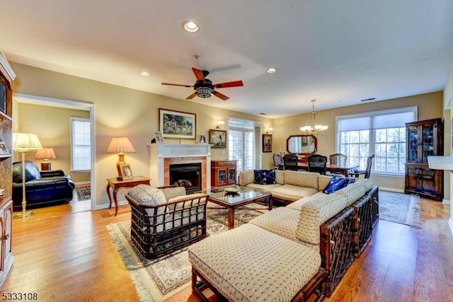 living room with ceiling fan with notable chandelier and light hardwood / wood-style flooring