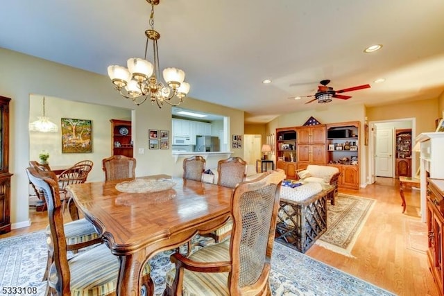 dining area with ceiling fan with notable chandelier and light hardwood / wood-style flooring