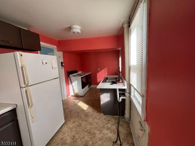 kitchen with sink, white appliances, and light carpet