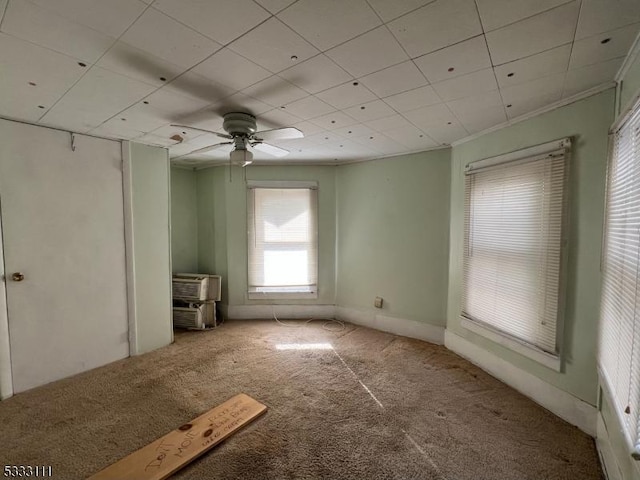 empty room with carpet floors, ceiling fan, crown molding, and a wall unit AC