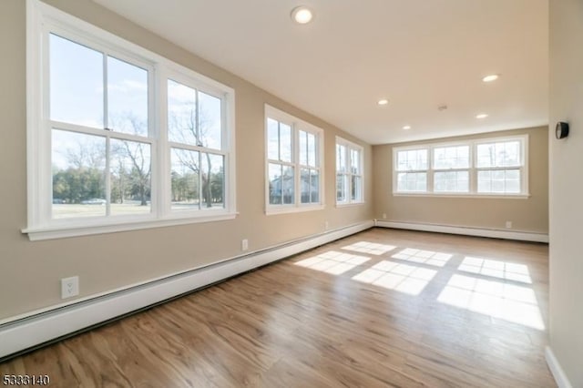 empty room with a baseboard heating unit and light hardwood / wood-style flooring