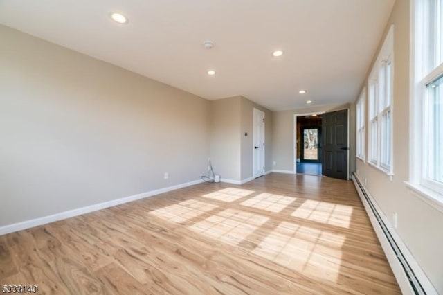 empty room with baseboard heating and light hardwood / wood-style flooring