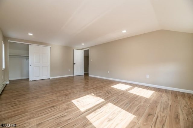 unfurnished bedroom with light hardwood / wood-style flooring, a closet, and vaulted ceiling