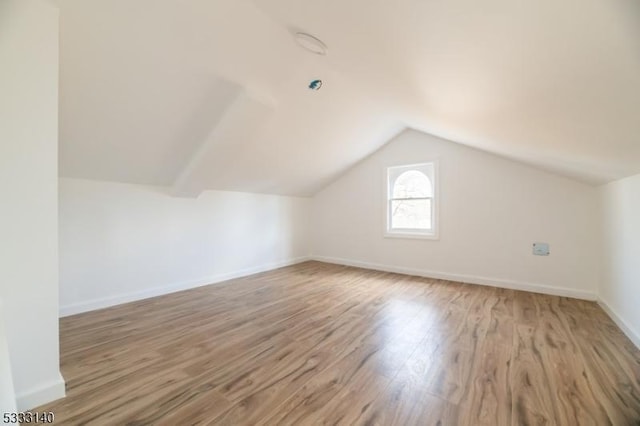 additional living space featuring light wood-type flooring and vaulted ceiling