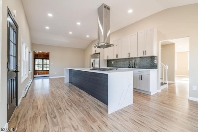 kitchen featuring lofted ceiling, island exhaust hood, white cabinetry, and a kitchen island