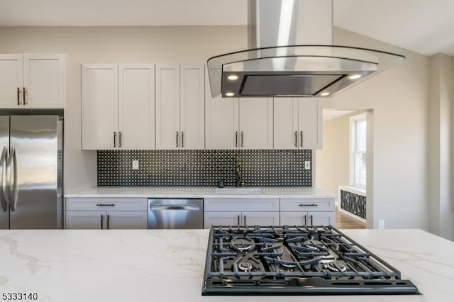 kitchen featuring white cabinets, appliances with stainless steel finishes, sink, island range hood, and light stone counters