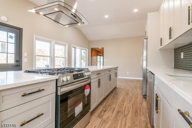 kitchen featuring vaulted ceiling, light hardwood / wood-style floors, island exhaust hood, white cabinetry, and appliances with stainless steel finishes