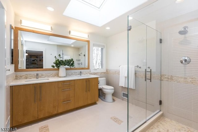 bathroom featuring walk in shower, vanity, a skylight, and toilet