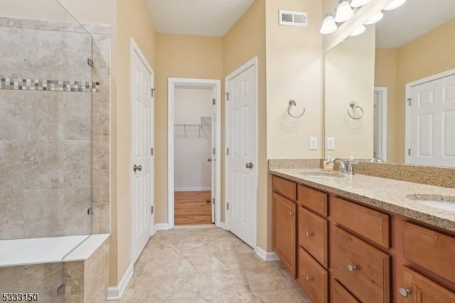 bathroom featuring tiled shower and vanity