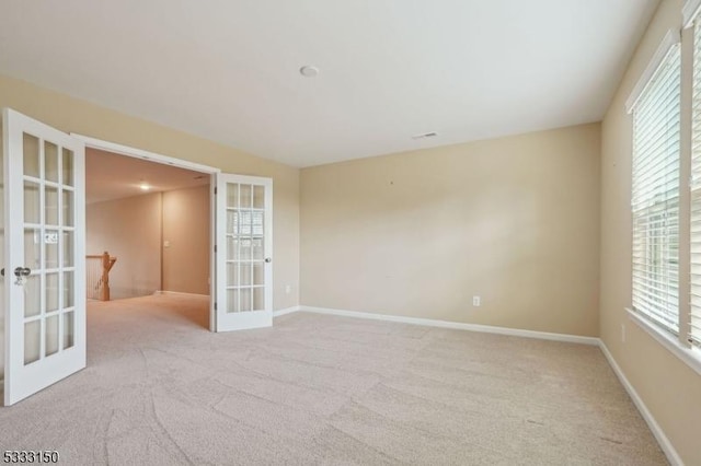 spare room featuring light colored carpet and french doors