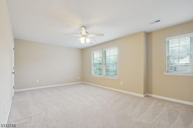 carpeted spare room with ceiling fan and plenty of natural light