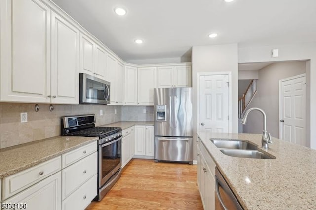 kitchen featuring white cabinets, sink, light stone counters, and stainless steel appliances