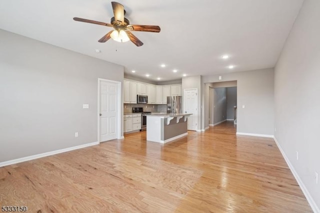 unfurnished living room featuring ceiling fan and light hardwood / wood-style flooring