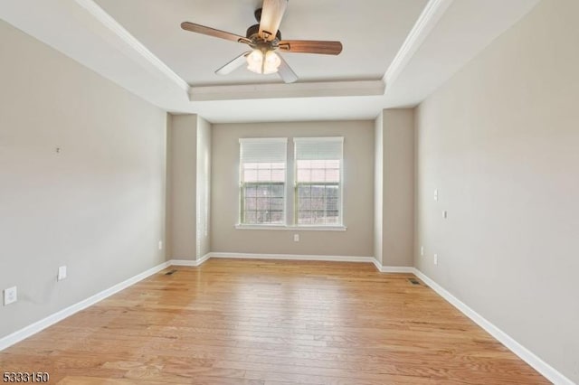 unfurnished room with ceiling fan, light wood-type flooring, a tray ceiling, and ornamental molding