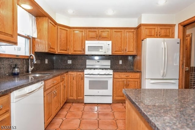 kitchen with decorative backsplash, sink, white appliances, and dark stone countertops