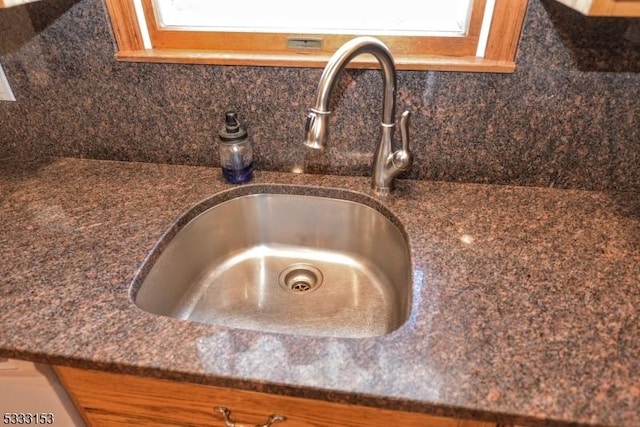 details with tasteful backsplash, dark stone counters, and sink