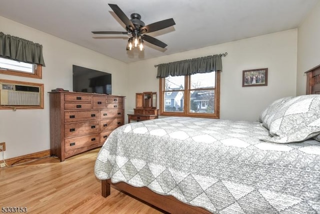 bedroom featuring ceiling fan, light hardwood / wood-style floors, and a wall mounted air conditioner