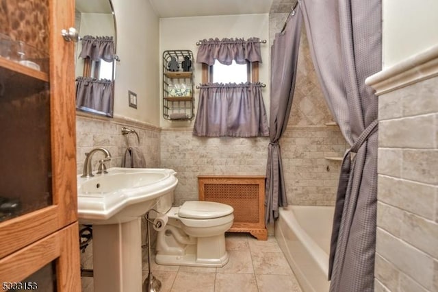 bathroom featuring toilet, tile patterned flooring, tile walls, and shower / bathtub combination with curtain