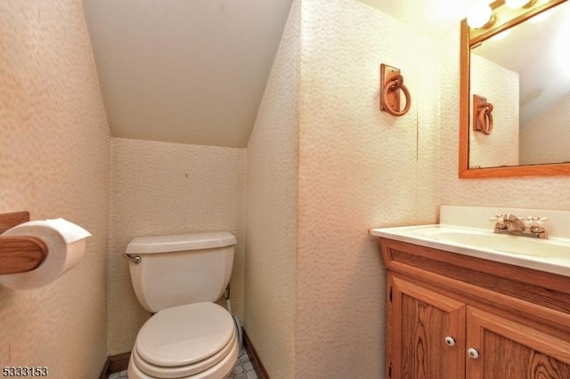 bathroom with toilet, vanity, and vaulted ceiling