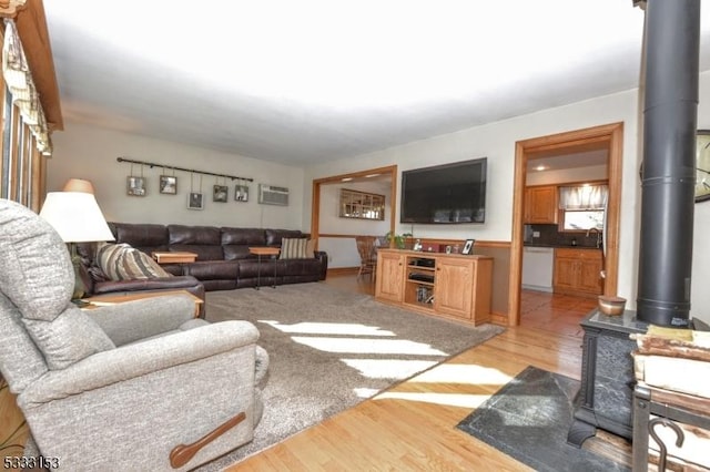 living room featuring a wall unit AC, a wood stove, light hardwood / wood-style flooring, and sink