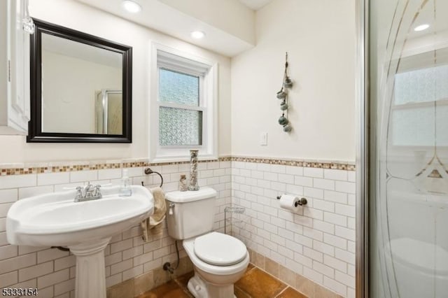 bathroom featuring toilet, tile walls, tile patterned floors, and walk in shower