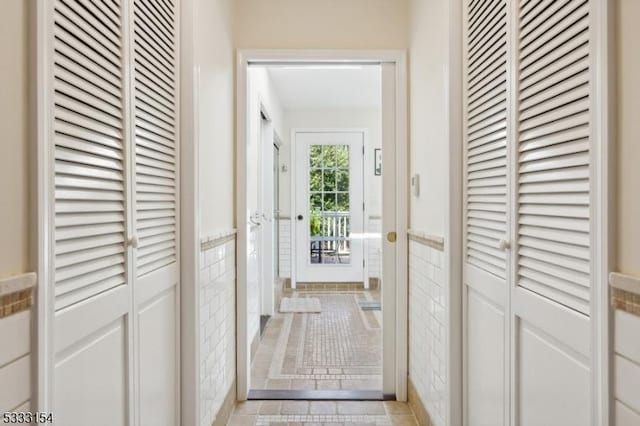 doorway featuring tile walls and light tile patterned flooring