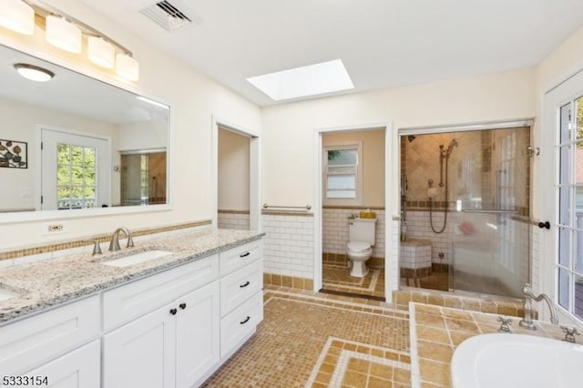 full bathroom with toilet, a skylight, tile walls, tile patterned floors, and shower with separate bathtub