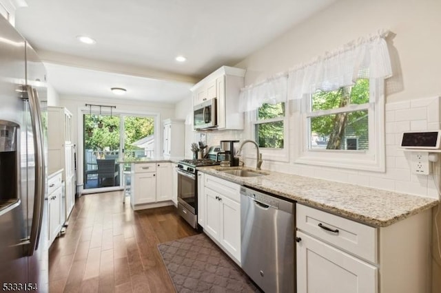 kitchen featuring dark hardwood / wood-style floors, sink, stainless steel appliances, white cabinets, and light stone counters