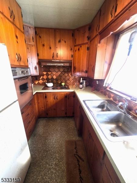 kitchen featuring tasteful backsplash, stovetop, sink, white refrigerator, and wall oven