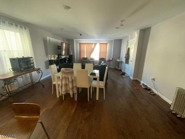 dining area featuring dark wood-type flooring and radiator