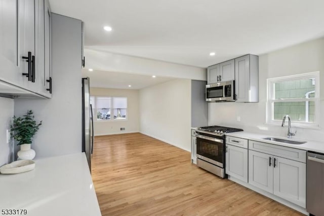 kitchen with gray cabinets, stainless steel appliances, light hardwood / wood-style flooring, and sink