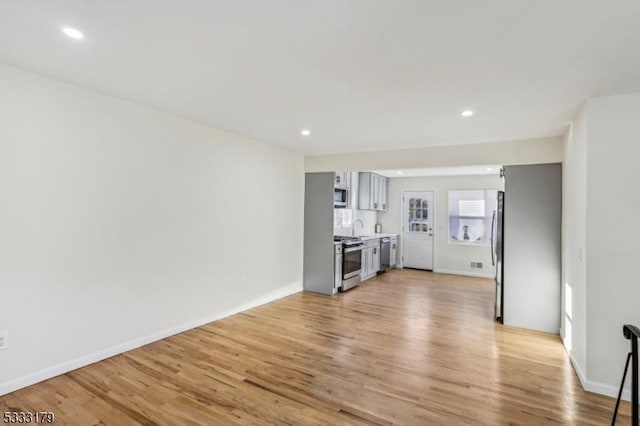 unfurnished living room with light hardwood / wood-style floors and sink