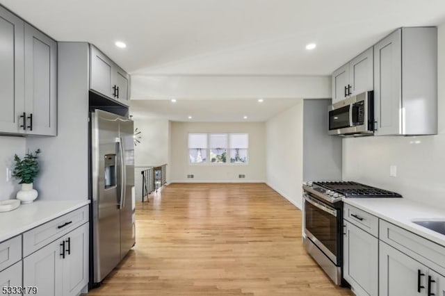 kitchen featuring light wood-type flooring, appliances with stainless steel finishes, sink, and gray cabinetry