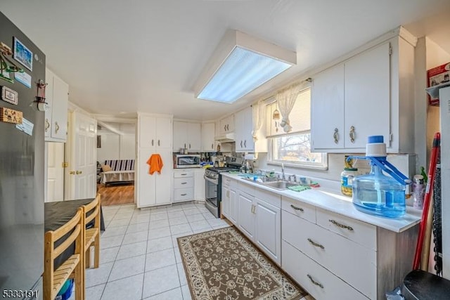 kitchen featuring sink, white cabinets, stainless steel appliances, and light tile patterned flooring