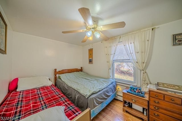 bedroom with ceiling fan, light hardwood / wood-style floors, and a baseboard radiator