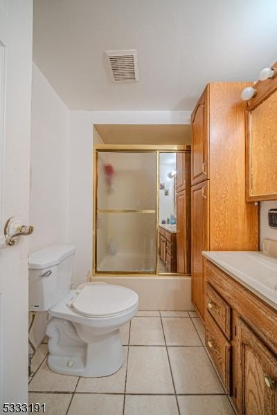 full bathroom with toilet, bath / shower combo with glass door, vanity, and tile patterned floors