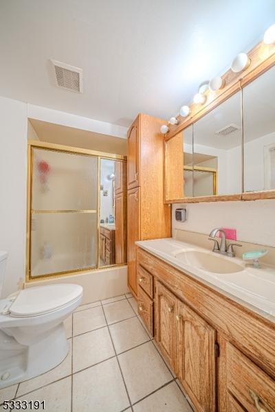 full bathroom featuring tile patterned floors, shower / bath combination with glass door, vanity, and toilet