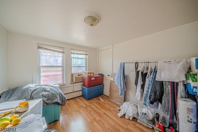 bedroom featuring light hardwood / wood-style floors, cooling unit, and a baseboard heating unit