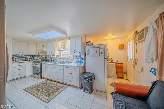 kitchen featuring appliances with stainless steel finishes, white cabinetry, sink, light tile patterned floors, and a wall mounted air conditioner