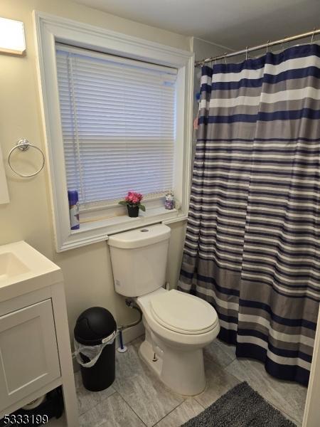 bathroom with toilet, vanity, tile patterned flooring, and curtained shower