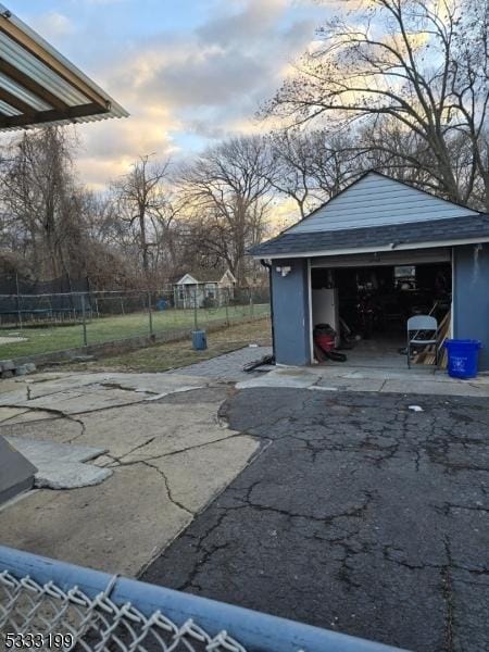 patio terrace at dusk with a garage and an outbuilding