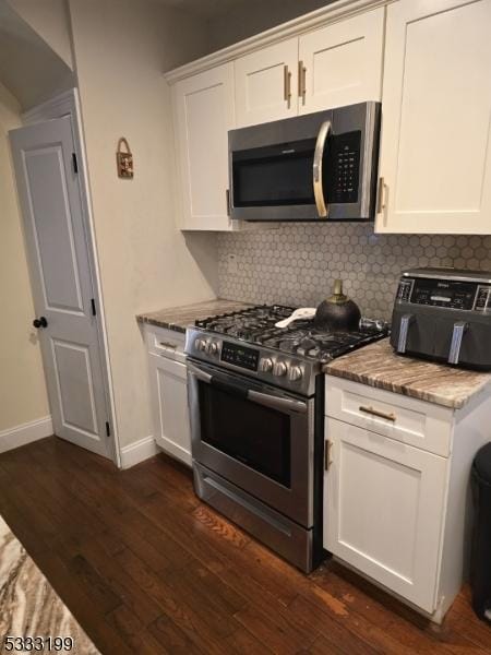 kitchen featuring white cabinetry, stainless steel appliances, dark hardwood / wood-style floors, backsplash, and stone counters