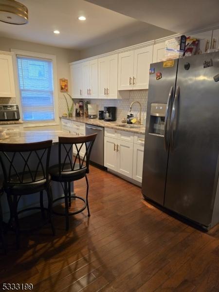 kitchen featuring dark hardwood / wood-style floors, stainless steel appliances, white cabinets, and sink