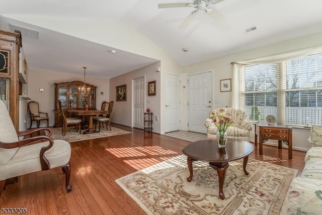 living room with lofted ceiling, ceiling fan with notable chandelier, and light hardwood / wood-style floors